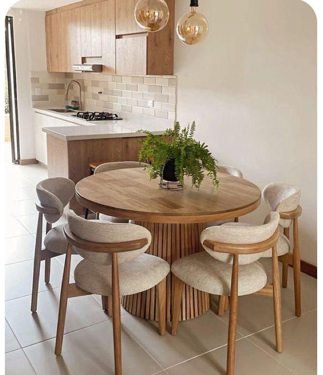 Mesa circular de madera con sillas grises en una cocina abierta